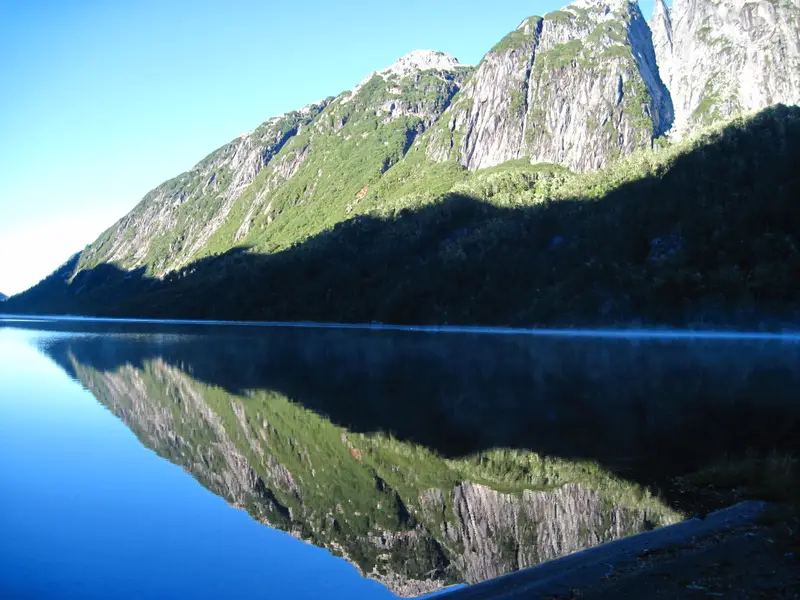 Lago quieto que refleja el cerro al amanecer